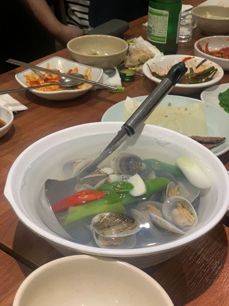 A high-satisfaction top-down shot of the clean, minimalist, and deeply comforting clear marsh clam soup at Hanseong.