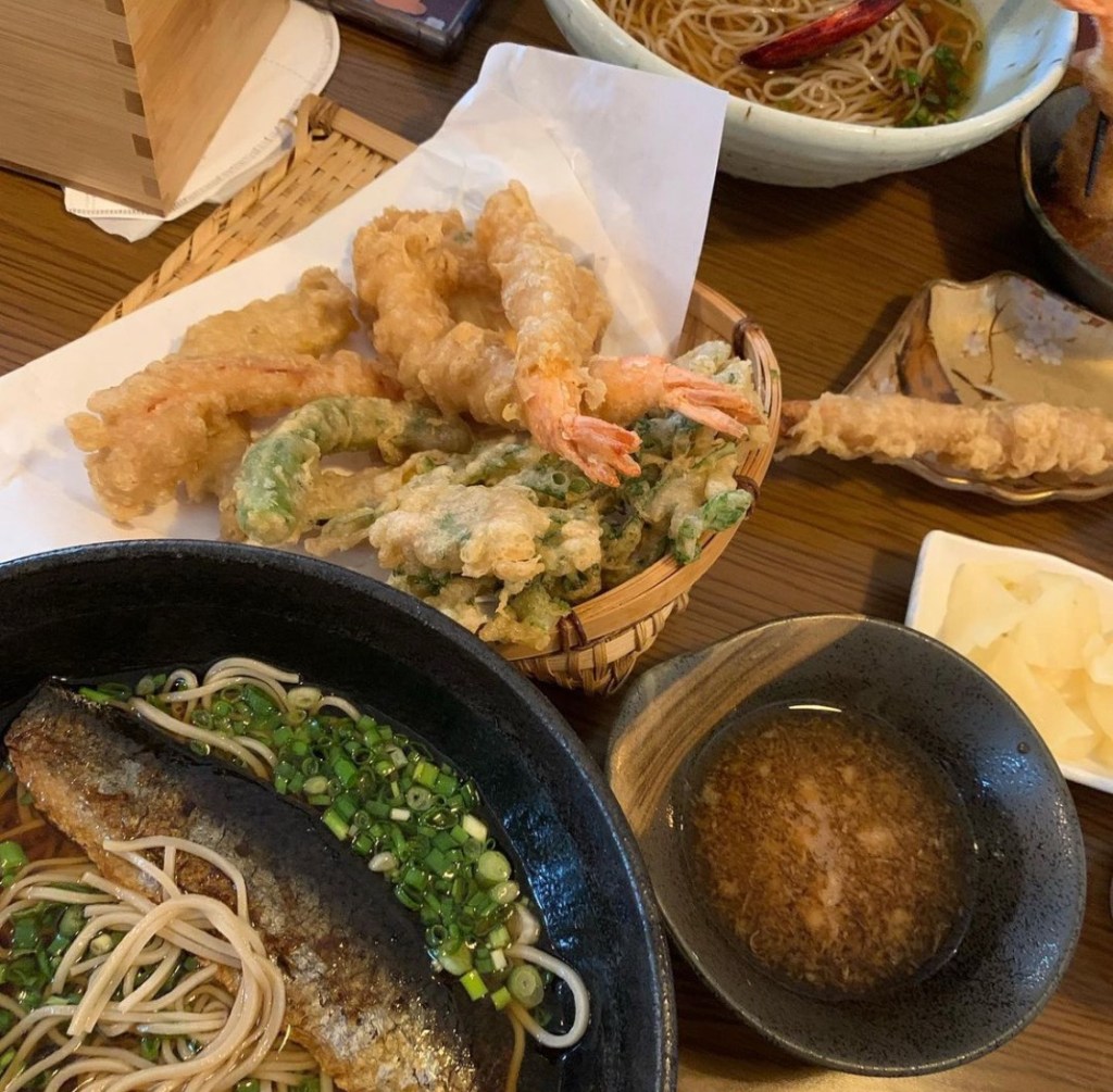 An aesthetic table setting featuring golden-brown Japanese crispy ebi tempura served alongside a chilled bowl of buckwheat noodles.