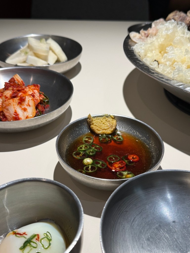 A mouthwatering focus on a glossy piece of Hanwoo beef dipping into a pungent, tangy premium dipping sauce.