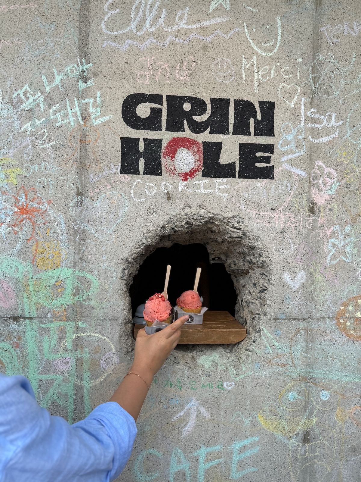 A trendy customer reaching out to receive a fresh ice cream cup from the secret serving portal at Green Hole Seongsu.