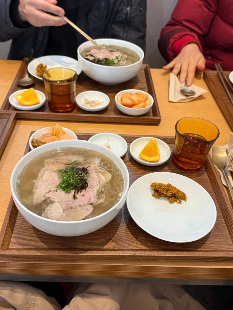 A beautiful minimalist top-down shot of the signature clear pork soup, Dwaeji-Gomtang, at modern restaurant Hau in Seongsu.