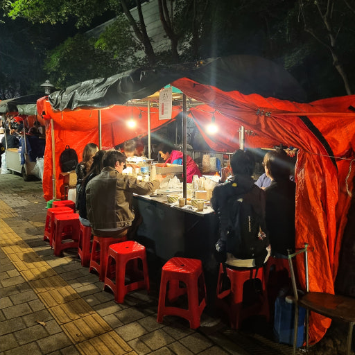 The iconic, atmospheric orange tarp of a traditional Korean street food tent glowing warmly at night.