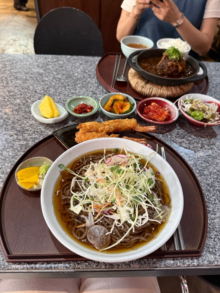 A high-satisfaction, giant bowl of cold buckwheat noodle soup layered with fine shaved ice slush, green scallions, and nori.