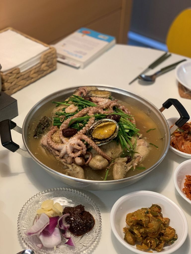 A cinematic close-up of fresh premium seafood simmering beautifully in a rich, nourishing chicken dashi broth.