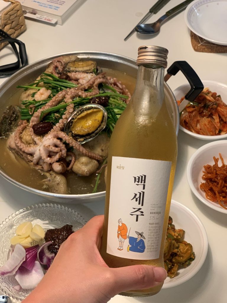 Pouring a glass of aromatic traditional Korean ginseng liquor to pair flawlessly with the herbal chicken soup.
