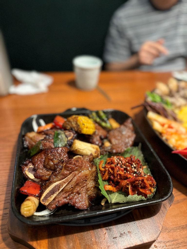 Thick, juicy slices of premium grilled sweet-soy LA Galbi served on a sizzling hot cast iron skillet.