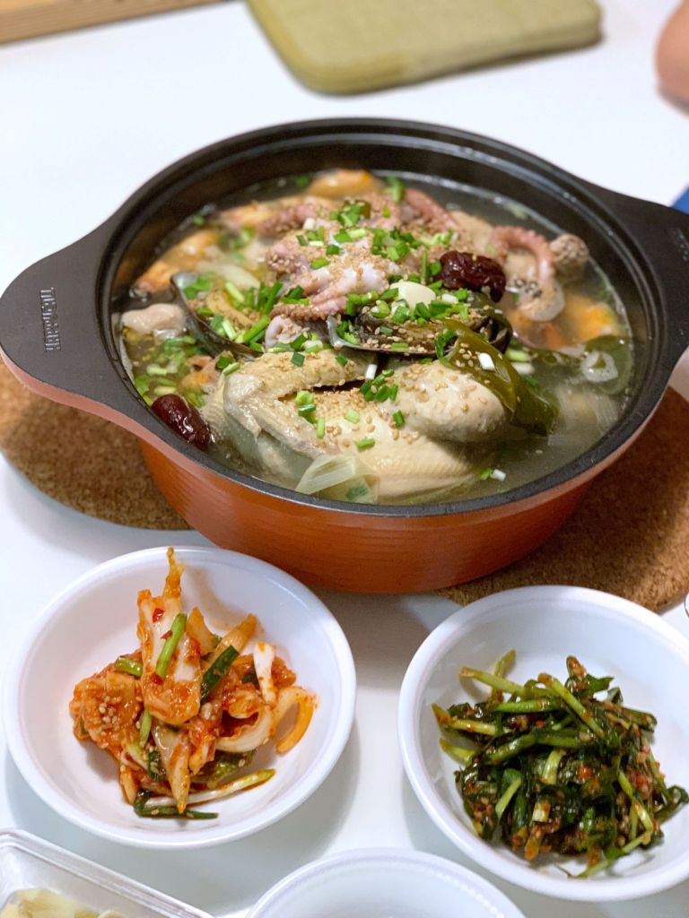 Elegant long strands of seasoned green onion kimchi, providing a sharp and savory counterpoint to the rich soup.