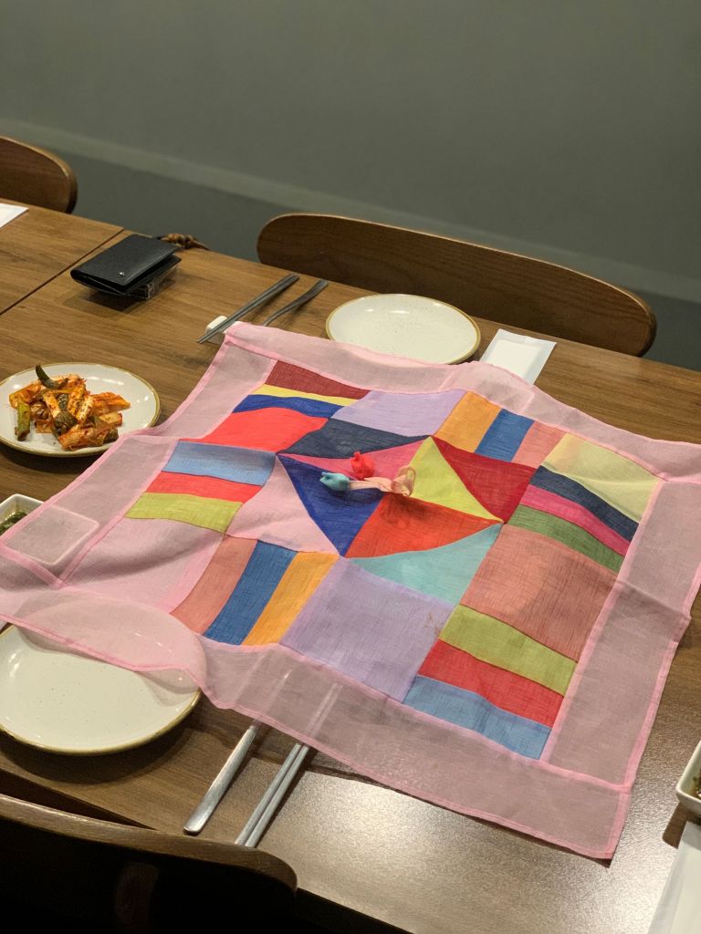 A beautifully crafted traditional Korean food cover placed elegantly over a gourmet dish at Woochan Sinsadong.