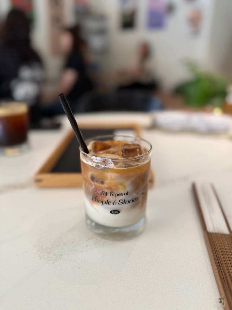 A cinematic focus on the layered aesthetic of an iced specialty milk beverage in a clean glass cup.