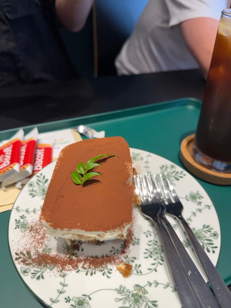 A high-satisfaction top-down view of classic mascarpone tiramisu dusted with rich cocoa powder at Bon Apre-Midi cafe.