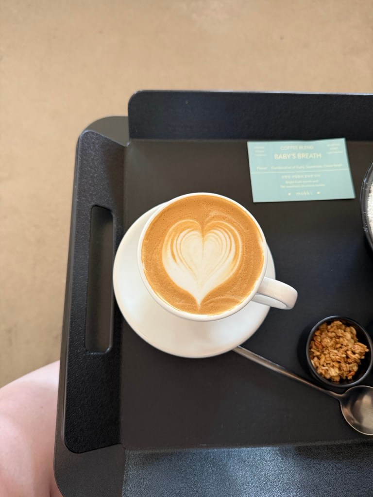 A warm lifestyle snapshot capturing someone taking a slow sip of hot coffee in the quiet atmosphere of Moki cafe.