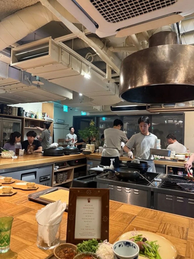 A warm lifestyle snapshot capturing guests enjoying a quiet and sophisticated Korean course dinner gathering.
