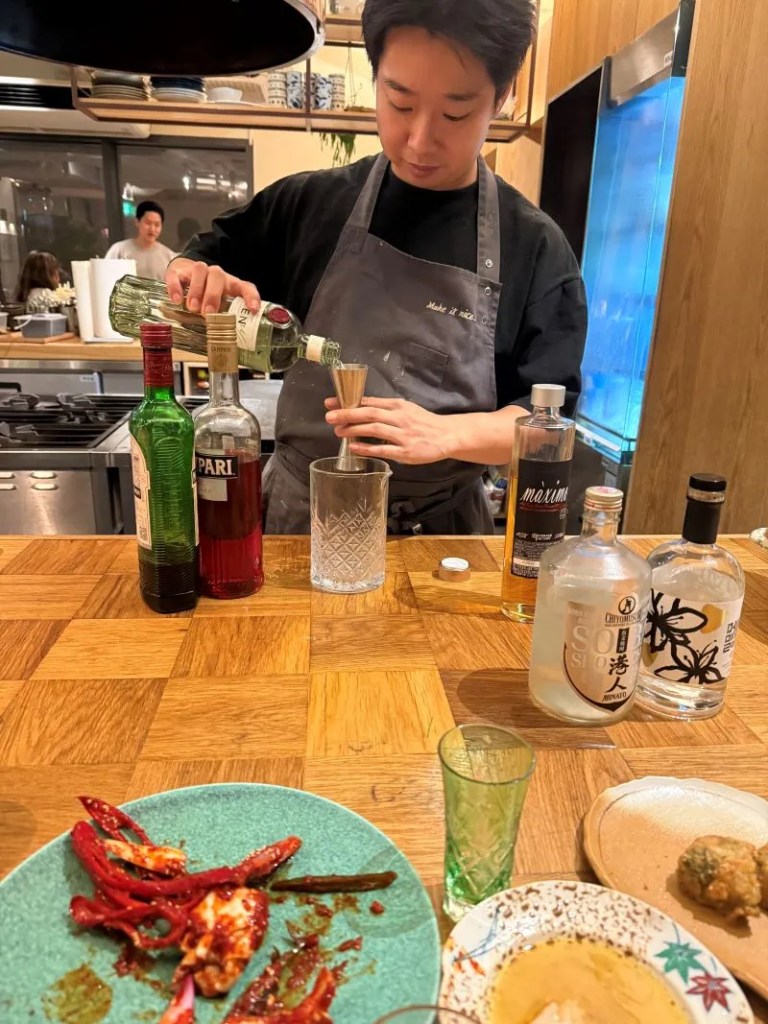 A warm lifestyle snapshot capturing guests savoring artisanal Korean cocktails during an evening dinner.