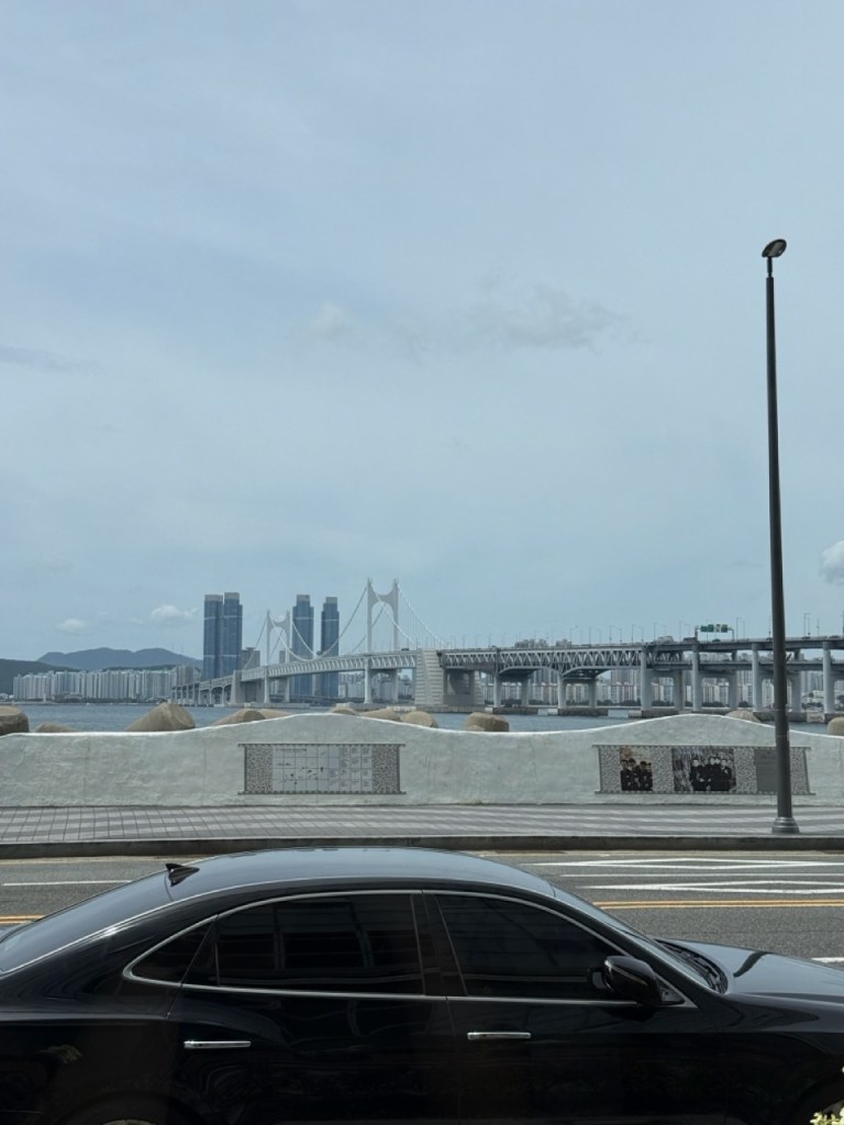 A high-satisfaction top-down view of the stunning Gwangan Bridge ocean view stretching through the large window of Cafe ALMA.
