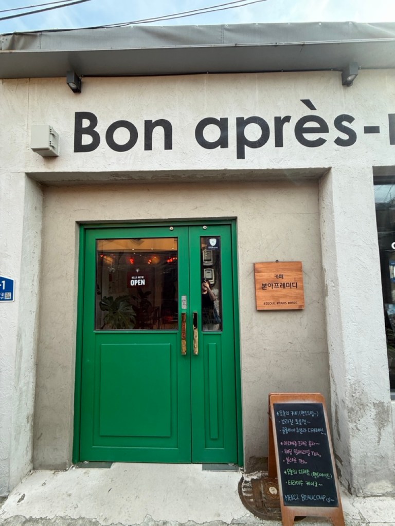 A high-satisfaction top-down view of the iconic deep green vintage entrance door at Bon Apre-Midi cafe in Mullae-dong
