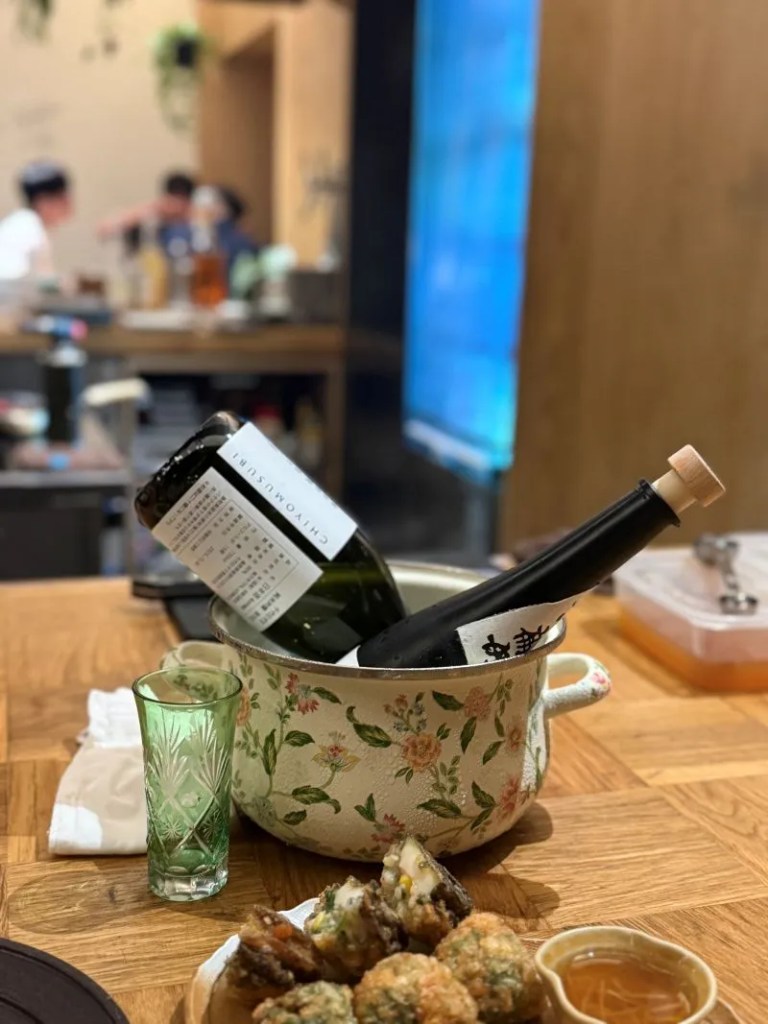 An aesthetic focus on a glass of chilled traditional liquor placed next to a fresh seasonal seafood course plate.