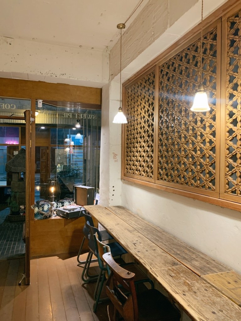 A cinematic focus on the warm wooden bench seating and soft ambient lighting inside Slot cafe Mullae.