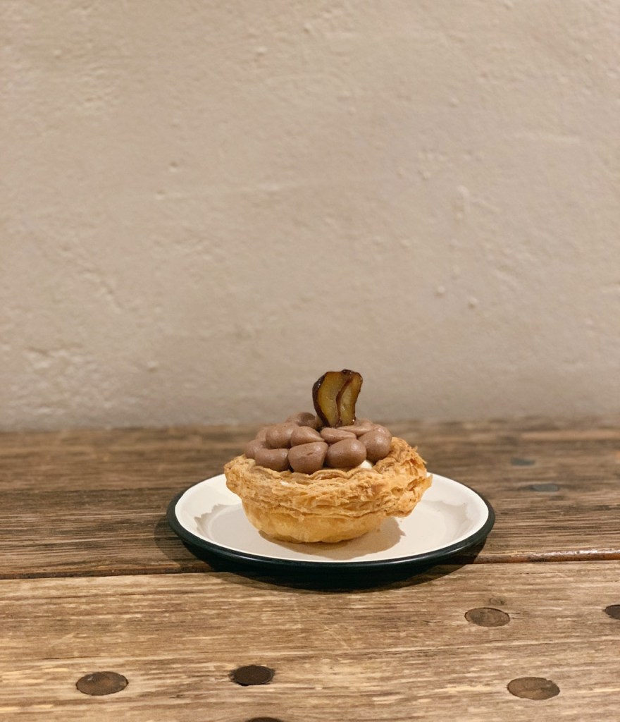 A beautiful close-up of a Zen-style wooden tray arranged neatly with a coffee glass and artisanal sweet bite.