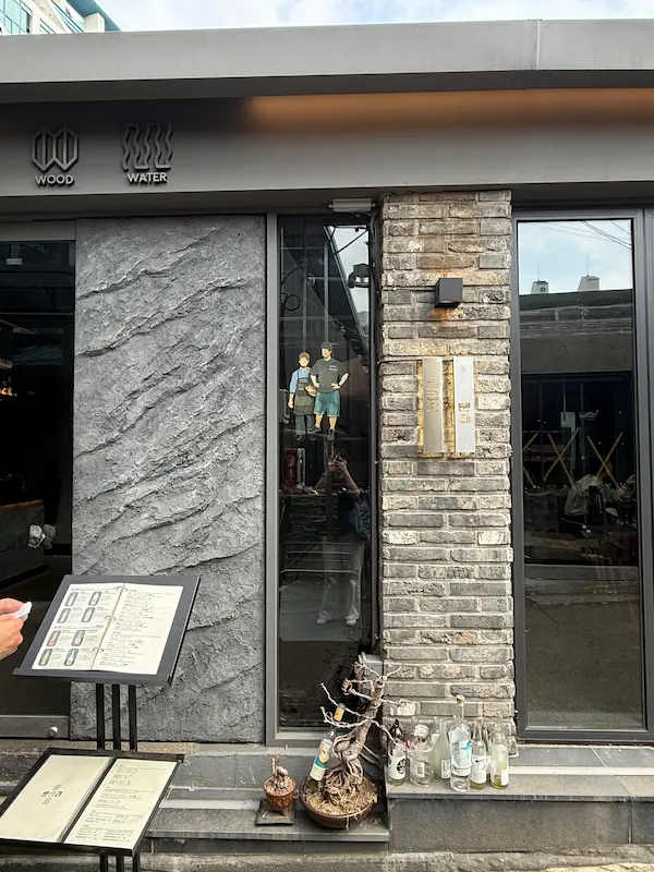 An aesthetic lifestyle snapshot showing diners enjoying drinks and small plates in trendy Mullae-dong.