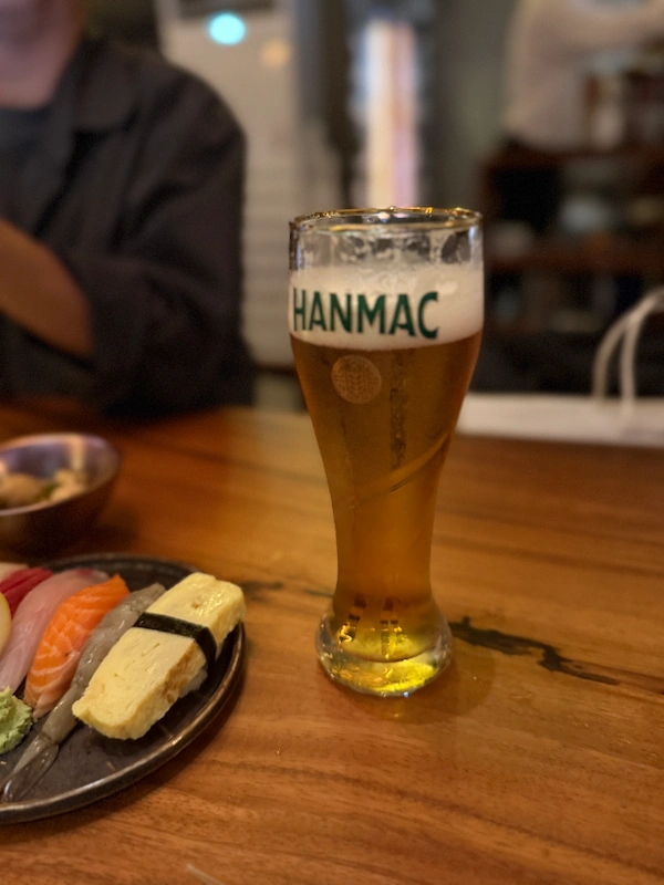A cinematic focus on Korean liquor being poured into a delicate glass alongside tapas dishes.