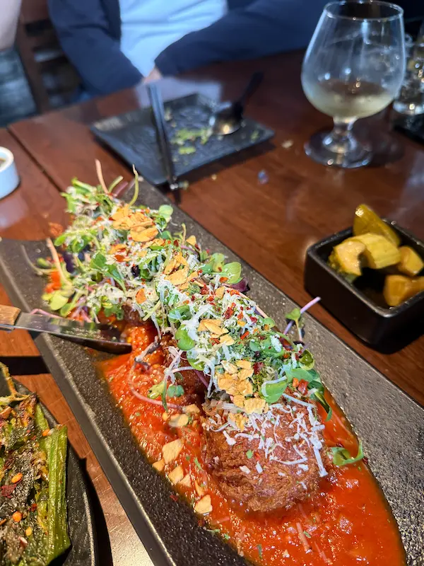 A high-satisfaction macro close-up of a signature fusion Korean delicacy beautifully plated with fresh garnishes.